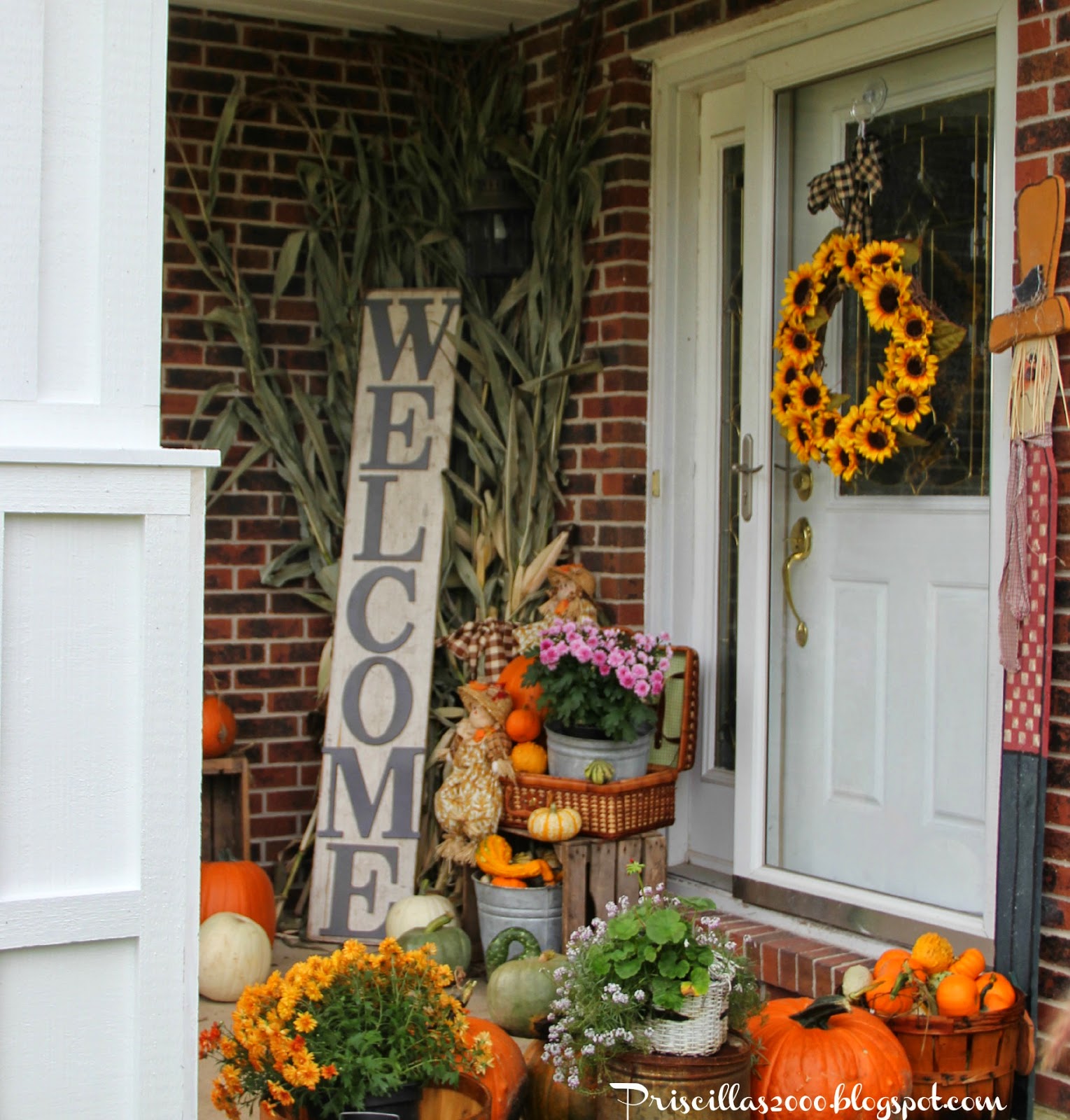 Beautiful Fall front porch with pumpkins, mums, and a sunflower wreath.